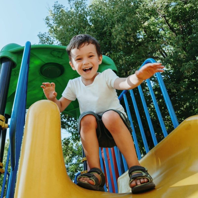 Happy,Preschooler,Boy,Playing,On,A,Slide,On,The,Playground